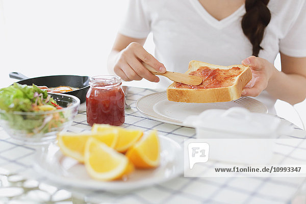 Young attractive Japanese woman having breakfast at home