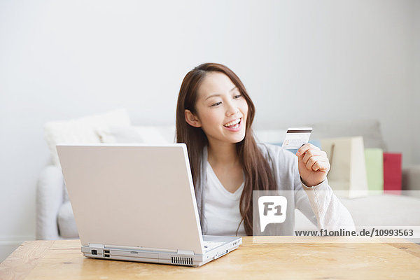 Young attractive Japanese woman doing online shopping at home