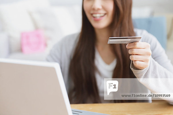 Young attractive Japanese woman doing online shopping at home