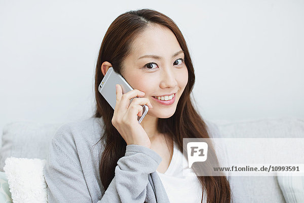 Young attractive Japanese woman on the phone on the sofa