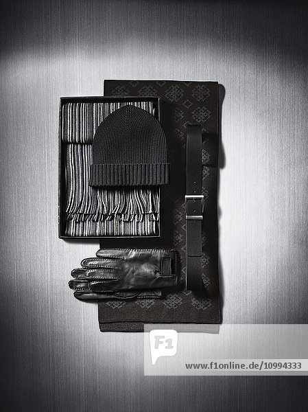 Schals  Handschuhe  Mütze und Gürtel auf metallischem Hintergrund im Studio