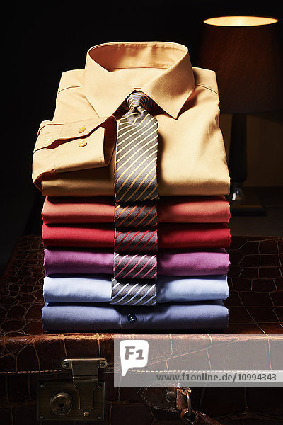 Stapel von Hemden mit Krawatten auf einem Koffer im Atelier