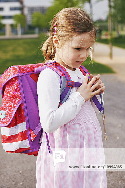 Porträt eines 5-jährigen Schulmädchens mit ihrer rosa und lila Schultasche,  Tagträume