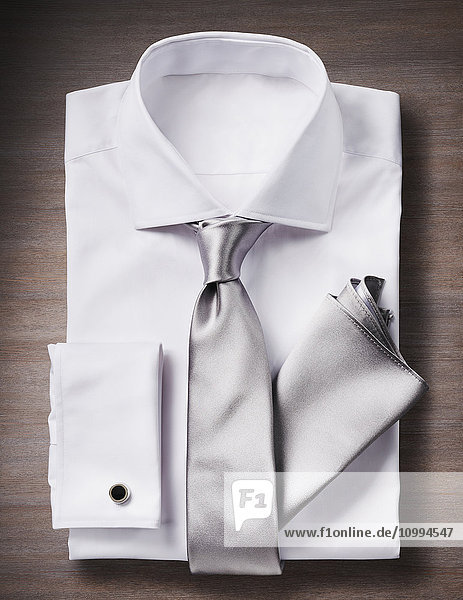 Weißes Hemd mit Krawatte  Einstecktuch und Manschettenknopf  Studioaufnahme auf Holzuntergrund