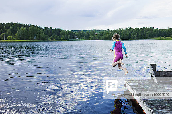 Mädchen springt vom Steg in den See  Schweden