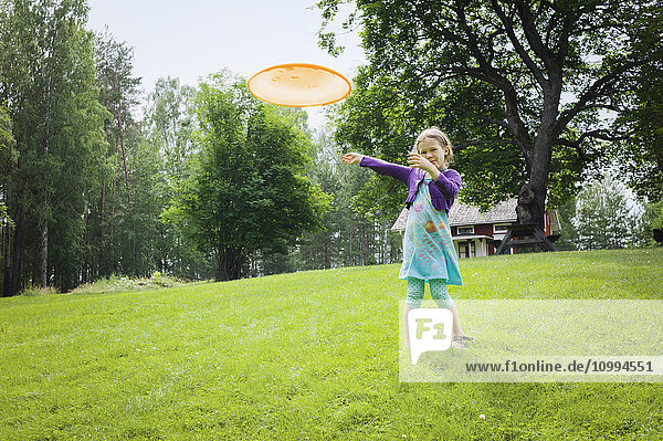 Junges Mädchen spielt mit einem Frisbee im Garten  Schweden