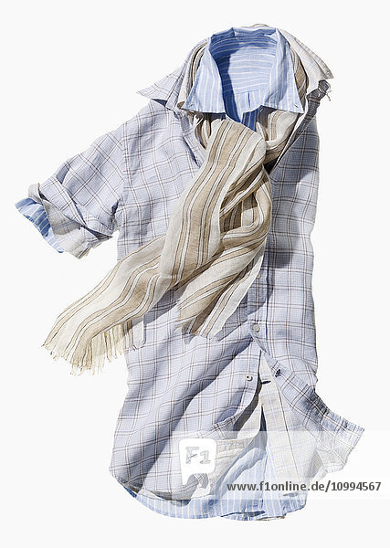 Drei kurzärmelige Hemden ineinander mit hellem Schal auf weißem Hintergrund