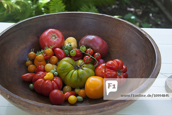 Antike Holzschüssel gefüllt mit einer Vielzahl von Heirloom-Tomaten