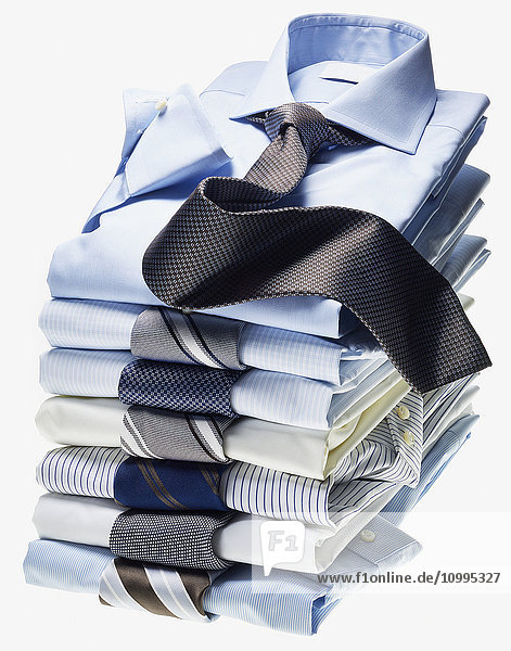 Stapel von mehrfarbigen Hemden mit Krawatten auf weißem Hintergrund