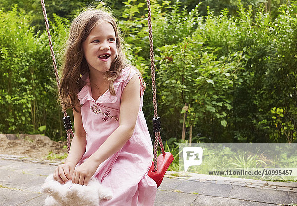 5 year old girl sitting on a swing in the garden  Germany