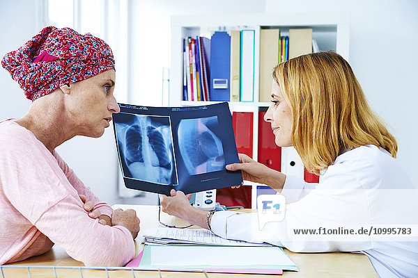 Ein Arzt erklärt einer Patientin das Ergebnis ihrer Röntgenaufnahme der Brust.