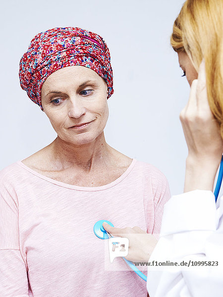 Doctor auscultating a woman suffering from cancer.