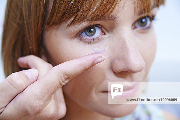 Woman inserting a contact lens.