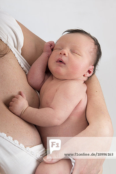 Ein schlafendes Baby in den Armen der Mutter.