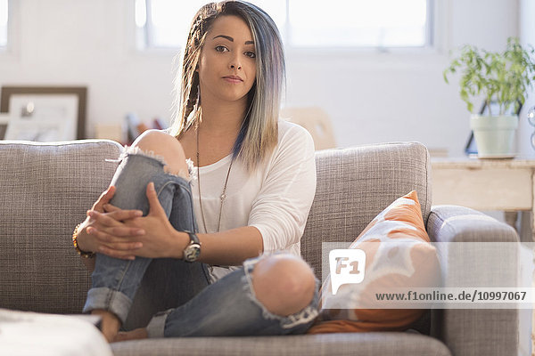 Selbstbewusste junge Frau auf dem Sofa sitzend