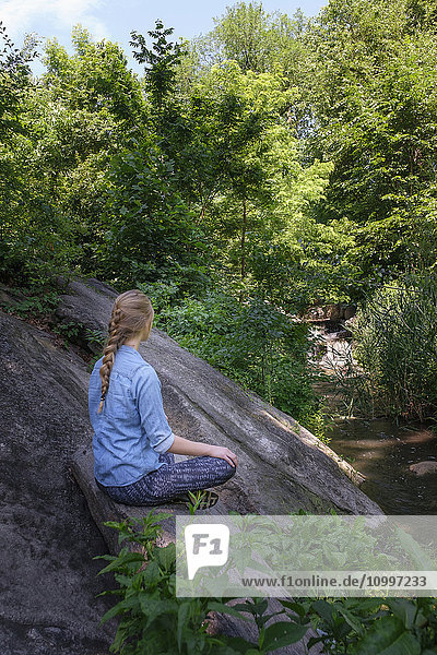 Frau sitzt auf einem Stein im Wald