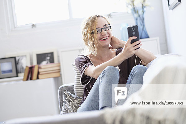 Woman sitting on sofa and using mobile phone