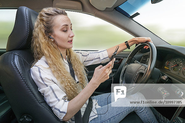 Frau benutzt Mobiltelefon beim Autofahren