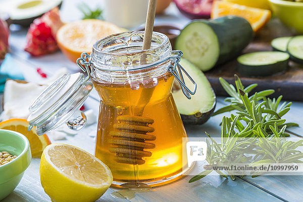 Jar of honey with dipper  lemon and fresh herbs