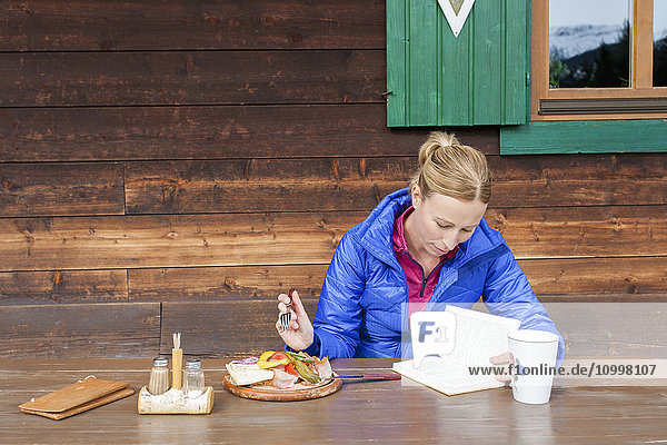 Austria Salzburger Land Maria Alm Mature woman reading book during lunch