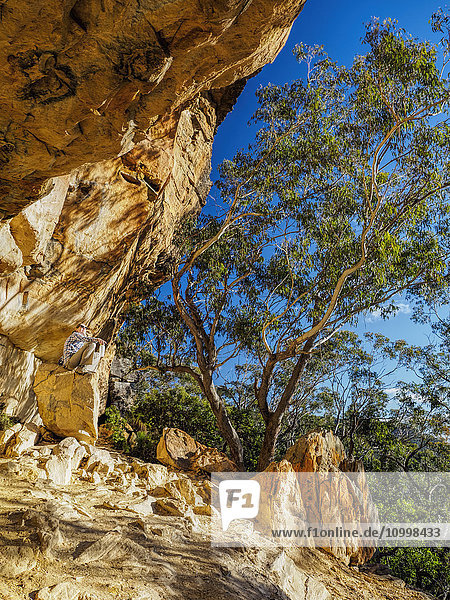 Australia  New South Wales  Blue Mountains  Mature woman resting on rock under cliff in mountain forest