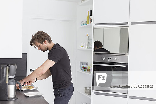 Mid-adult man preparing breakfast in modern kitchen