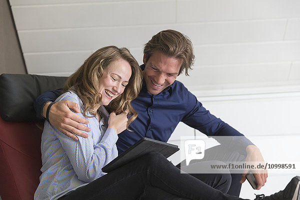 Mid-adult couple looking at tablet and laughing