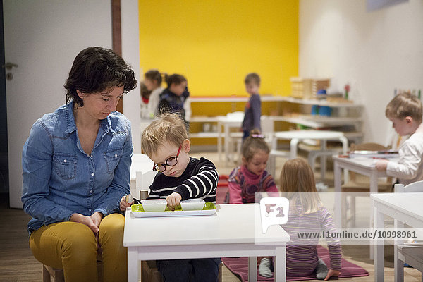 Reportage in einer zweisprachigen Montessori-Schule in Haute-Savoie  Frankreich  die Kinder im Alter von 2 bis 6 Jahren unterrichtet. Die 2- bis 6-Jährigen sind alle in einer Klasse  um die Sozialisierung zu fördern: die Älteren kümmern sich um die Jüngeren  was das Selbstvertrauen der Älteren stärkt und die Motivation der Jüngeren erhöht. Die in der Schule angewandte Montessori-Pädagogik zielt darauf ab  die Autonomie  den Wunsch und die Neugier des Kindes zu entwickeln. Jede nutzlose Hilfe  die dem Kind gegeben wird  wird zu einem Hindernis für seine Entwicklung   sagte Maria Montessori. Den Kindern stehen bestimmte Materialien zur Verfügung  und jedes Kind kann die Übung auswählen  die es durchführen möchte. Bei dieser Übung muss das Kind kleine Bohnen mit Hilfe eines Löffels umfüllen.