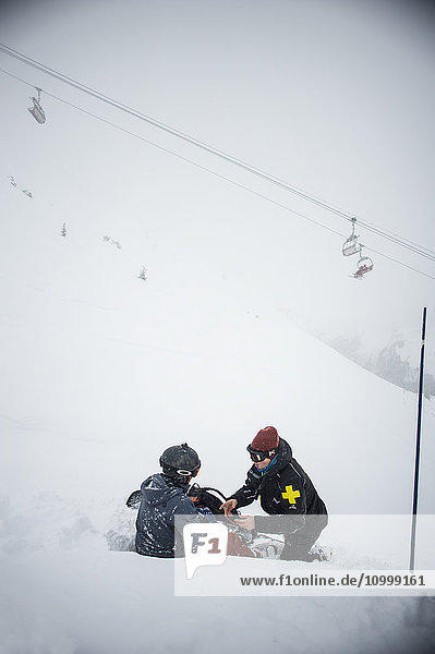 Reportage with a ski patrol team at the Avoriaz ski resort in Haute Savoie  France. The team are responsible for marking out the ski slopes  providing first aid to skiers  evacuations on the slopes as well as off piste and controlled avalanches. The ski patrol team rescue a snowboarder who has injured his shoulder.