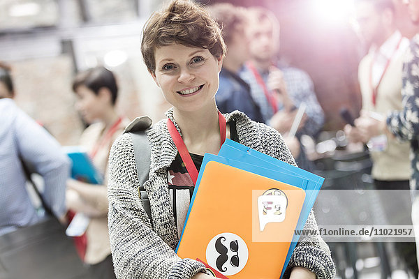 Portrait lächelnde junge Frau mit Laptop bei der Technologiekonferenz