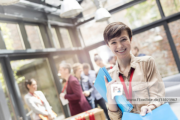 Portrait lächelnde junge Frau beim Verteilen von Päckchen auf der Konferenz