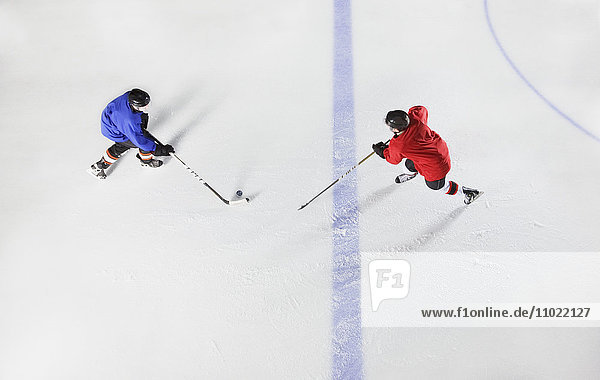 Overhead-Ansicht Hockeyspieler auf dem Weg zum Puck auf dem Eis