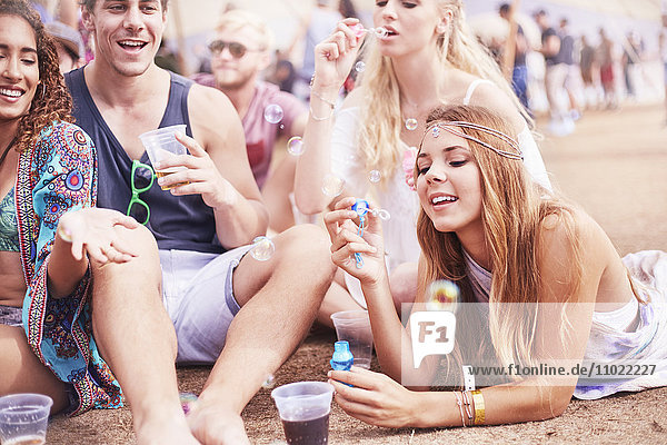 Junge Freunde hängen auf dem Musikfestival herum und blasen Blasen.