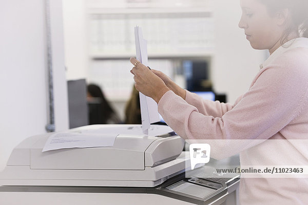 Businesswoman making copies at photocopier in office