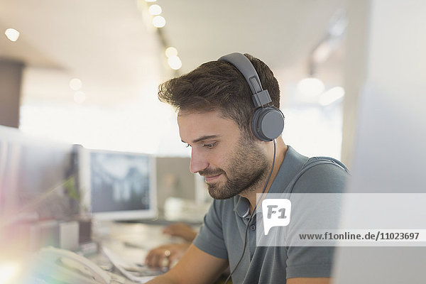 Creative businessman with headphones working in office