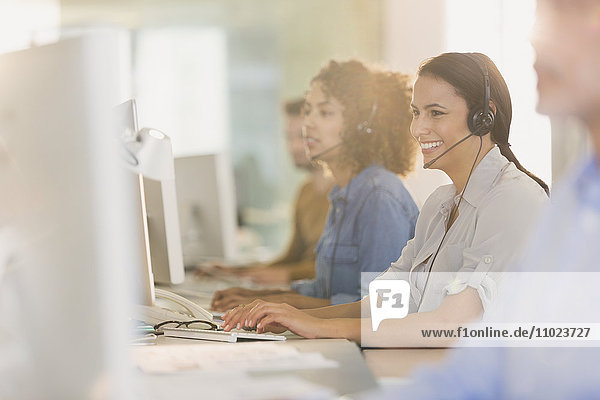 Smiling businesswoman with headset working at computer in office