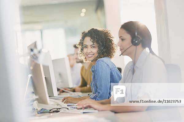 Portrait lächelnde Geschäftsfrau mit Headset bei der Arbeit am Computer im Büro
