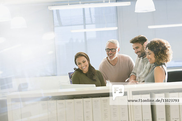 Lächelnde Geschäftsleute arbeiten am Computer im Büro