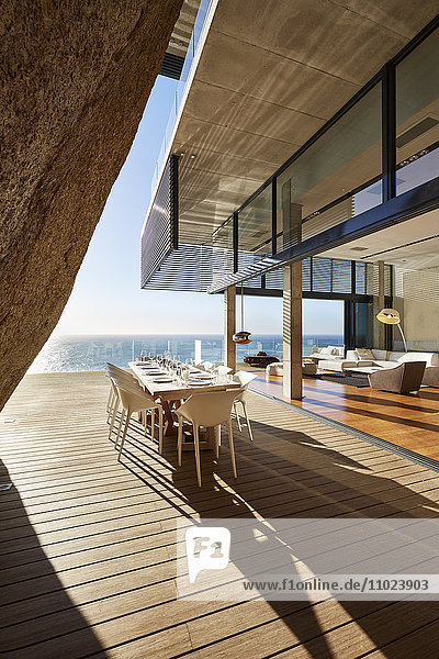 Moderner Luxus-Esstisch auf sonniger Terrasse mit Meerblick