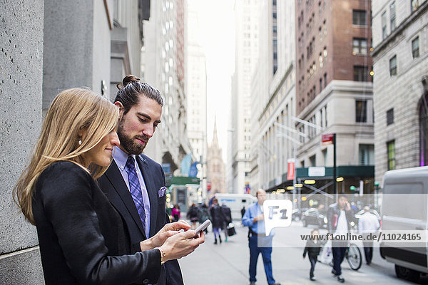 Woman showing phone to businessman against buildings in city