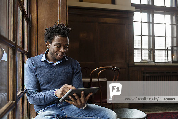 Young man using tablet while sitting at cafe