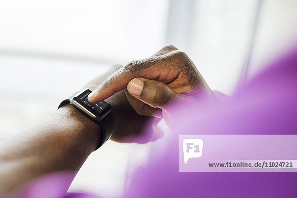 Cropped image of businessman using smart watch in office