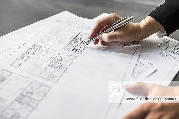 Cropped image of female architect working on blueprint