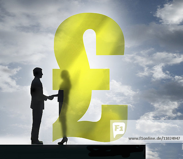 Geschäftsmann und Geschäftsfrau schütteln die Hände hinter durchscheinendem britischem Pfundsymbol