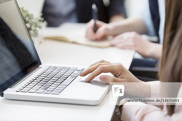 Cropped image of businesswoman using laptop at table in meeting