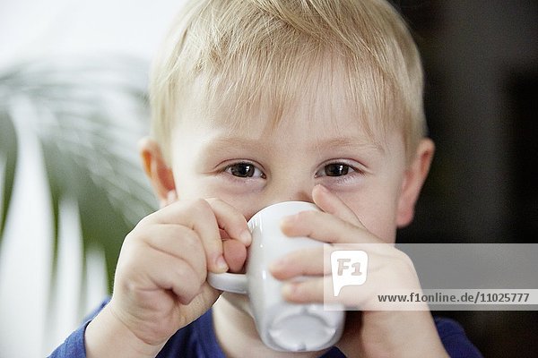 Blond boy drinking from cup