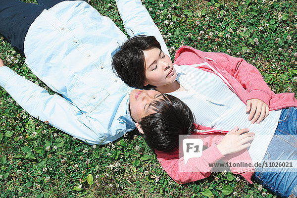 Junges japanisches Paar liegt im Gras