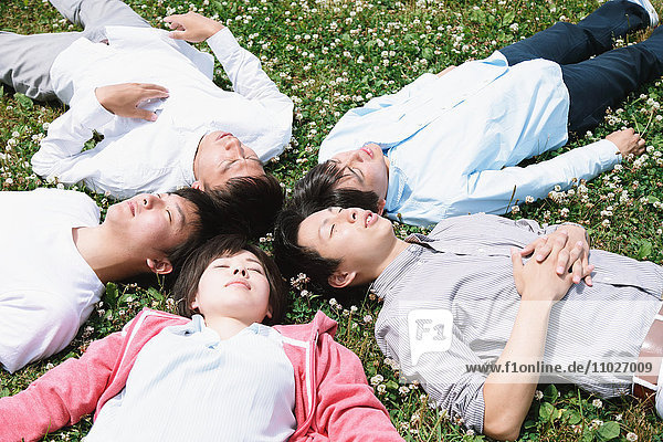 Gruppe junger japanischer Freunde  die im Gras liegen