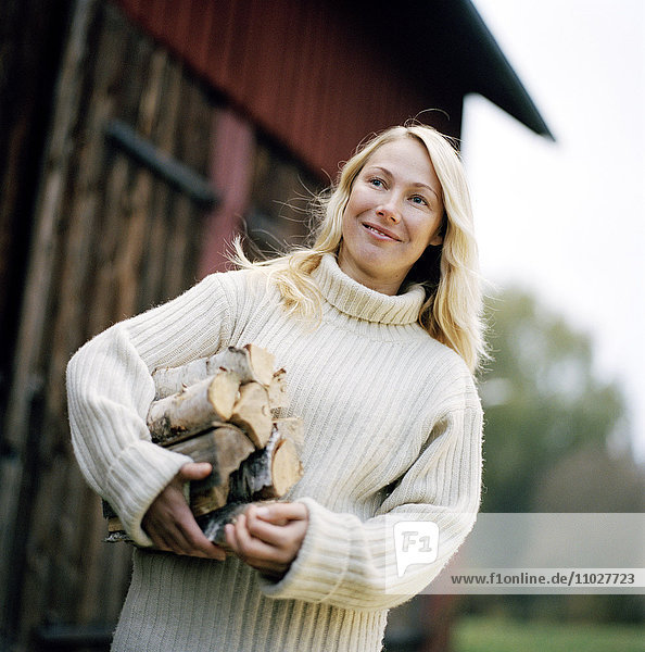 A blond woman carrying wood.
