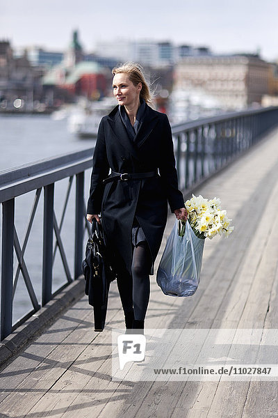Frau beim Spaziergang mit Narzissen in der Einkaufstasche